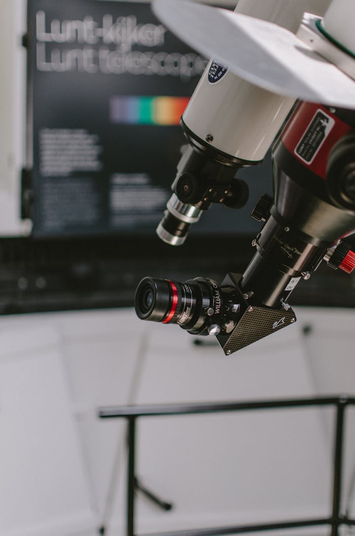 Close-up of a telescope fitted with a camera in a modern laboratory setting.